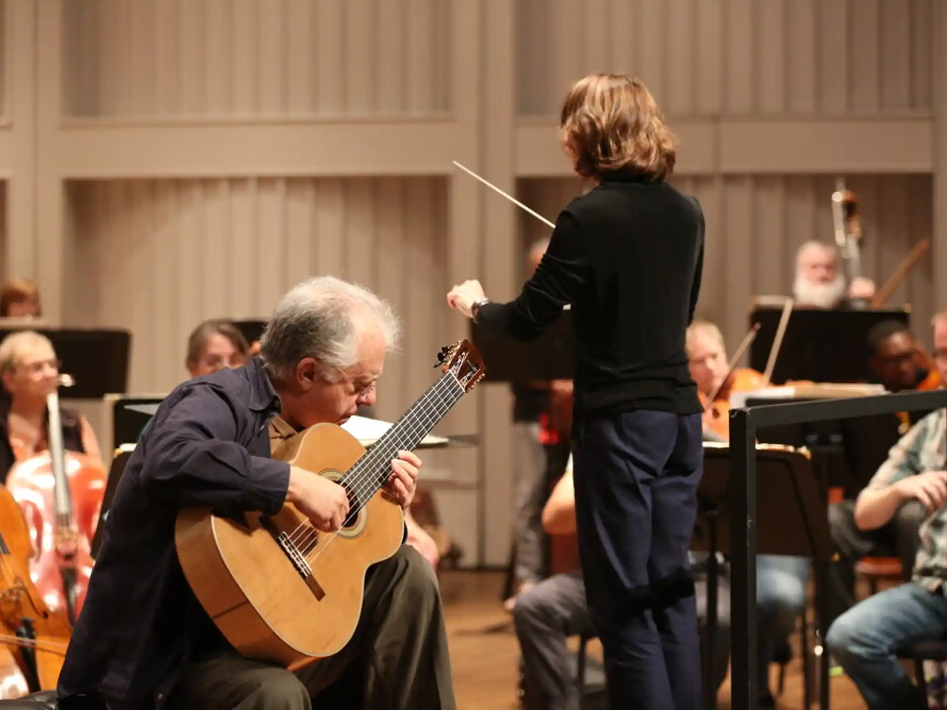 a man playing a guitar next to a woman playing an instrument