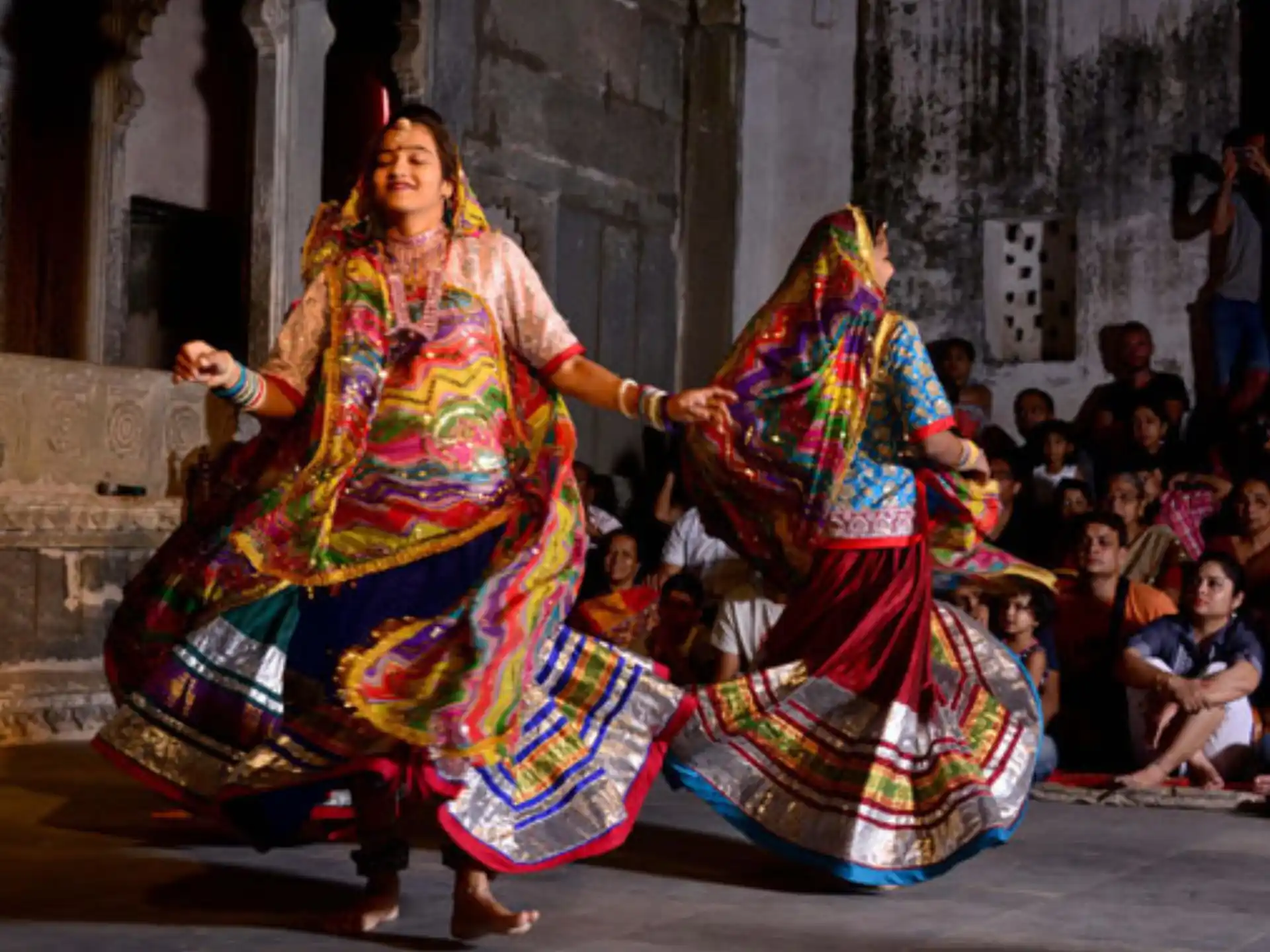 a person in a colorful dress dancing in front of a crowd