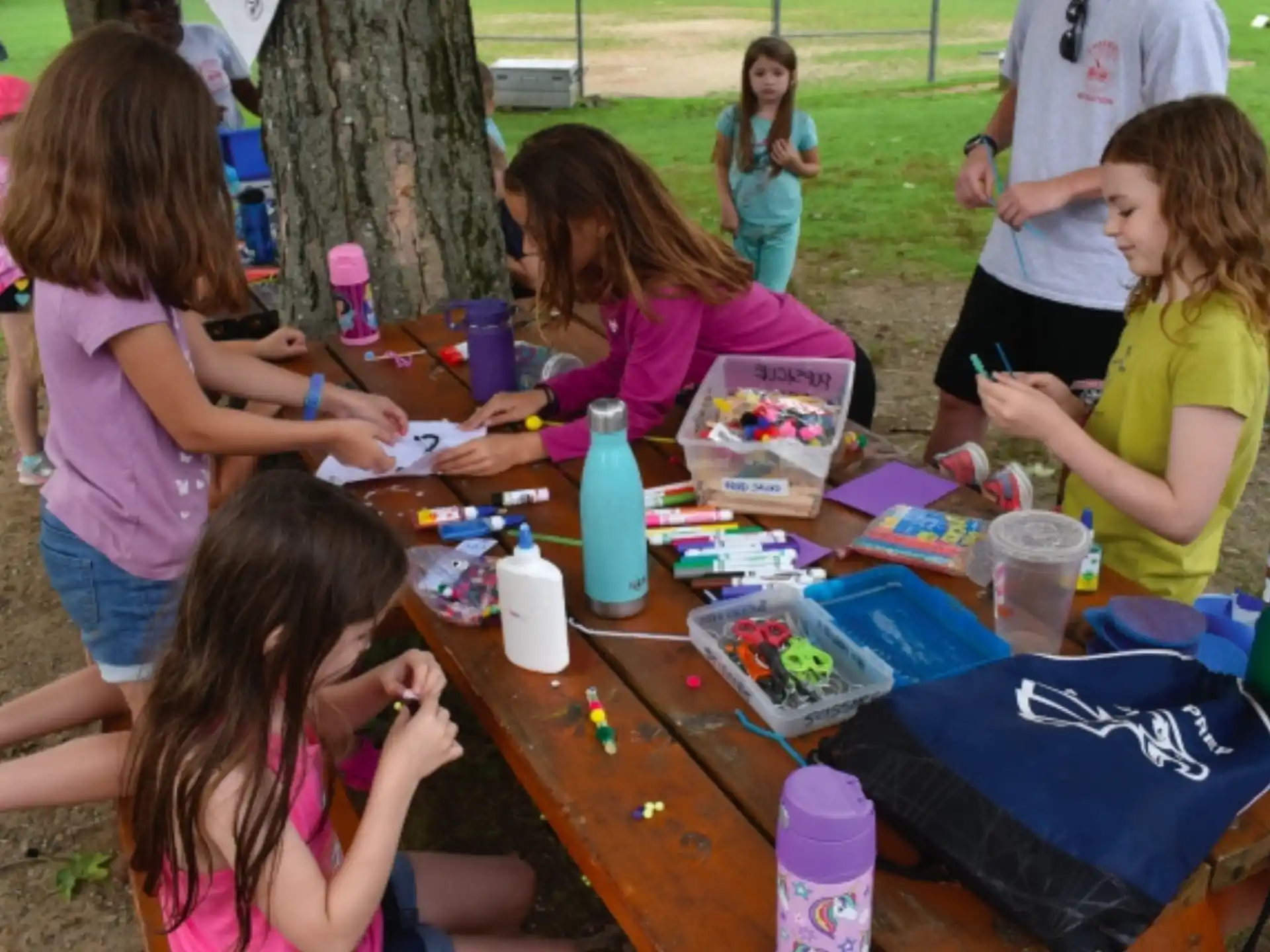 a group of children sitting at a table outside