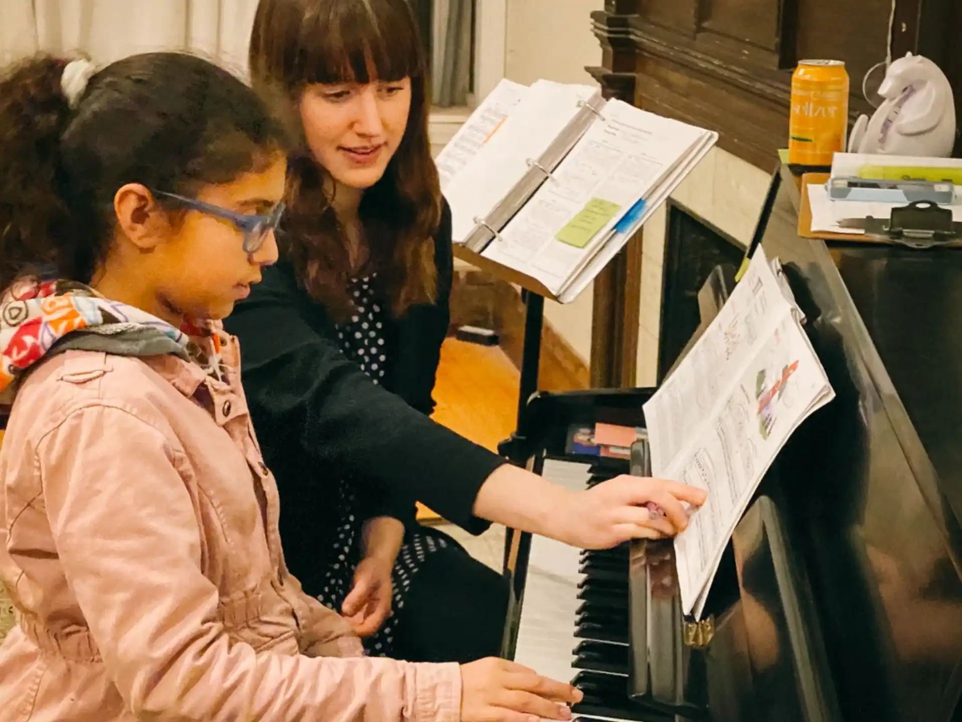 a woman playing a piano with a man sitting at the piano