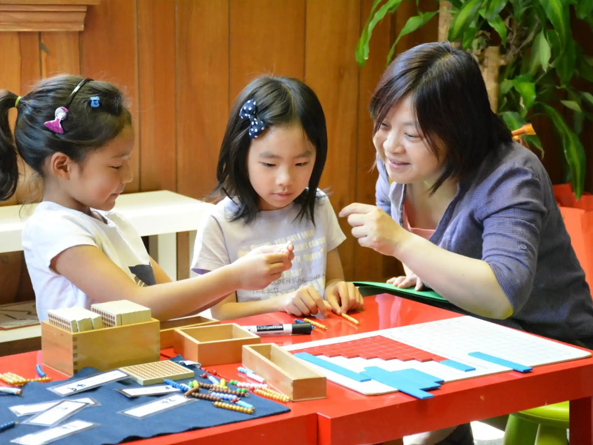 a woman and two girls sitting at a table with colorful paper