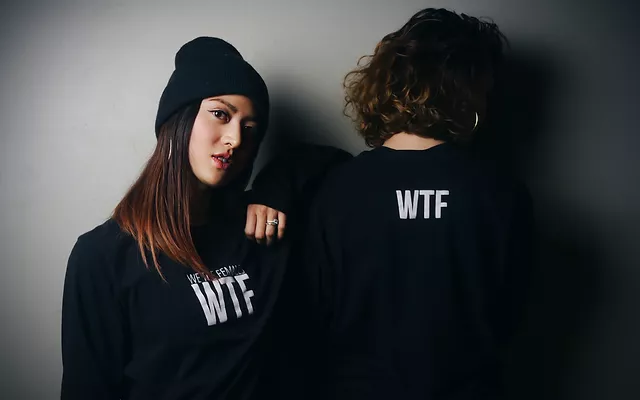 a woman with her hand on her shoulder and a man with a hat