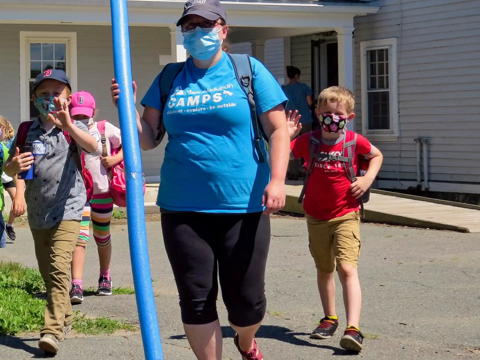a person wearing a mask and a mask walking with kids