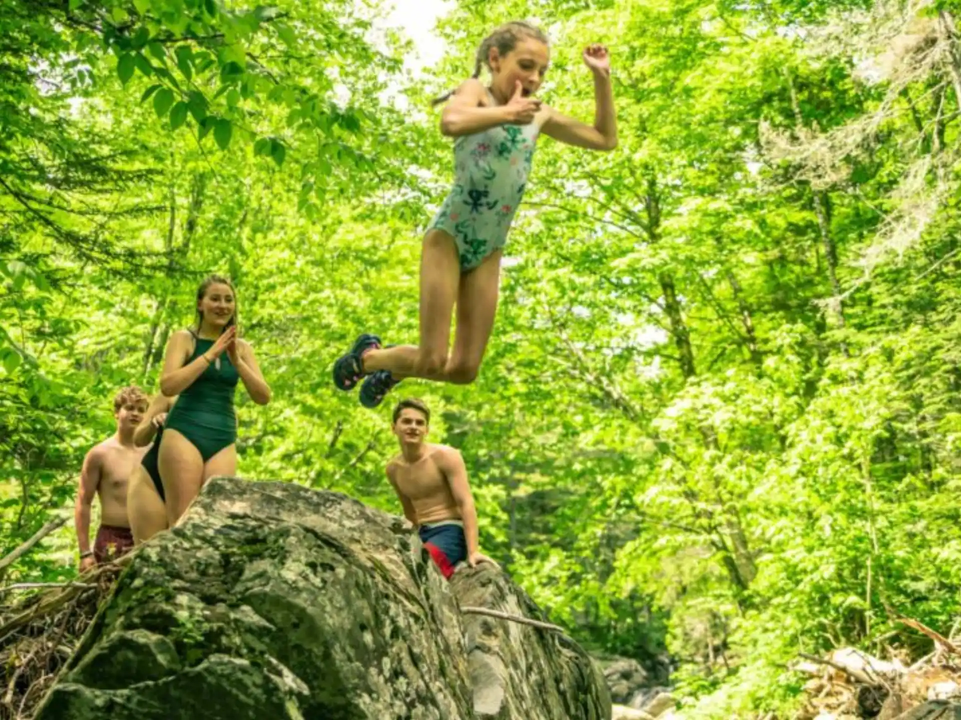 a group of kids jumping off a rock