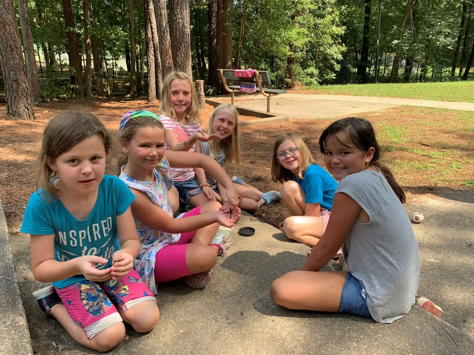 a group of girls sitting on the ground outside