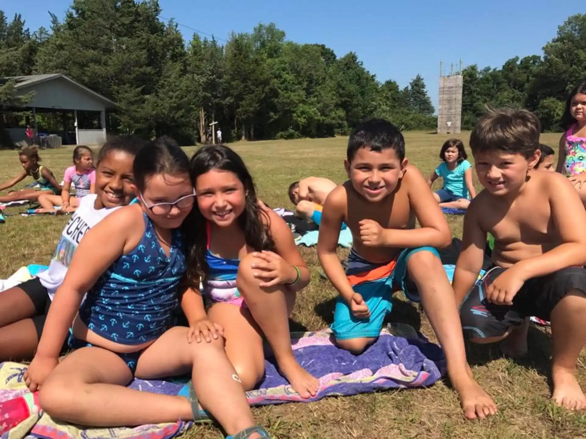 a group of people sitting on a blanket on a beach