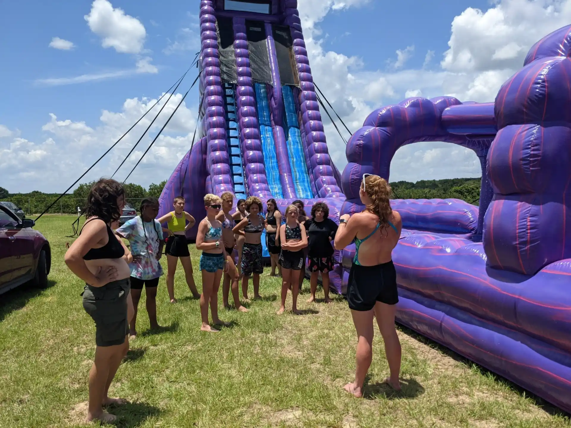 a group of people standing in front of a large purple and blue slide