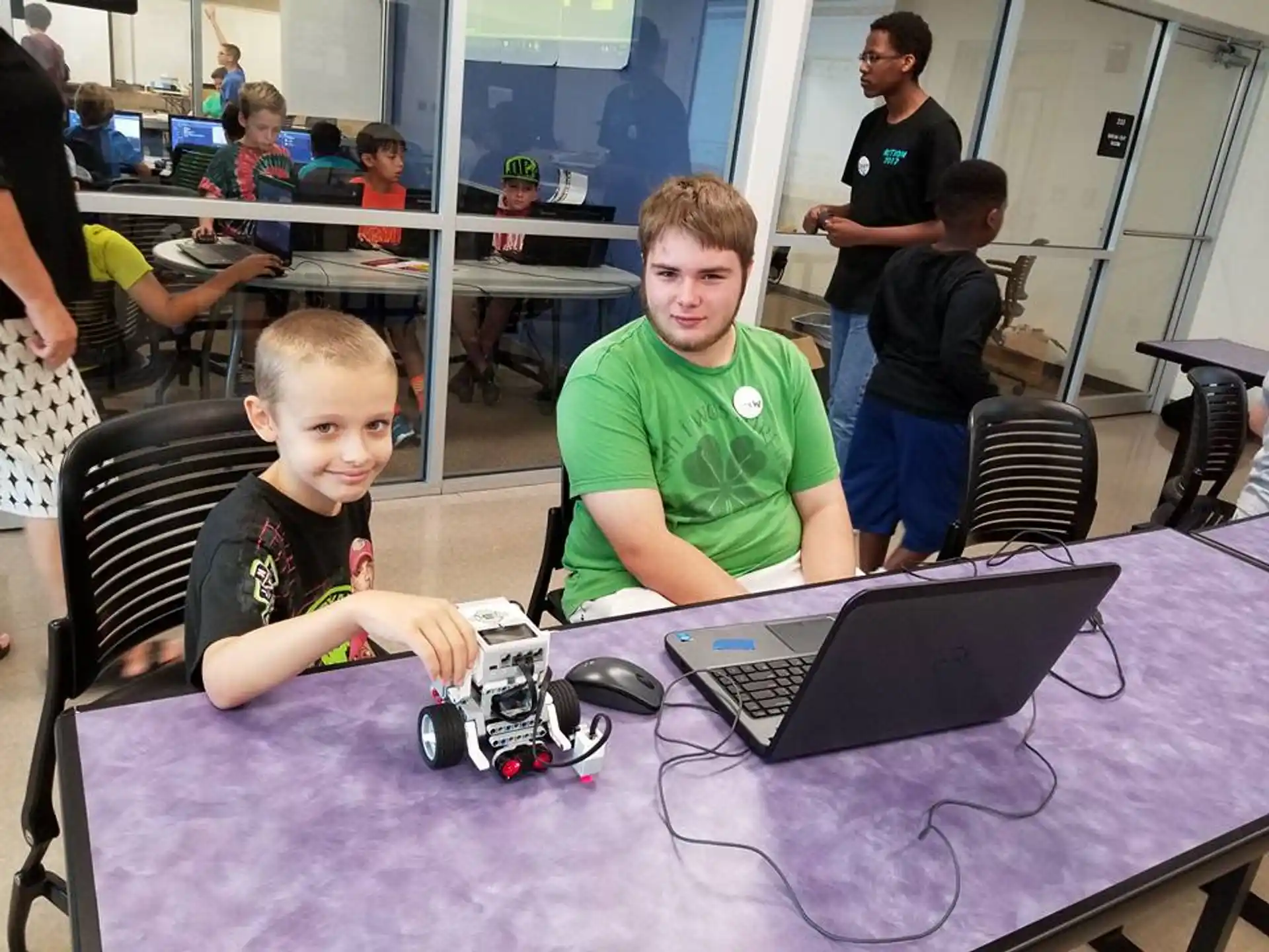 a boy and a boy sitting at a table with a laptop