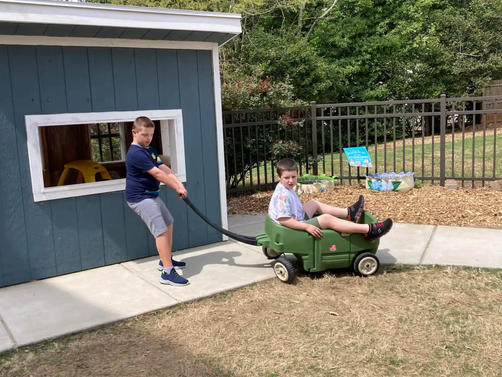 a boy pushing a person on a lawn mower