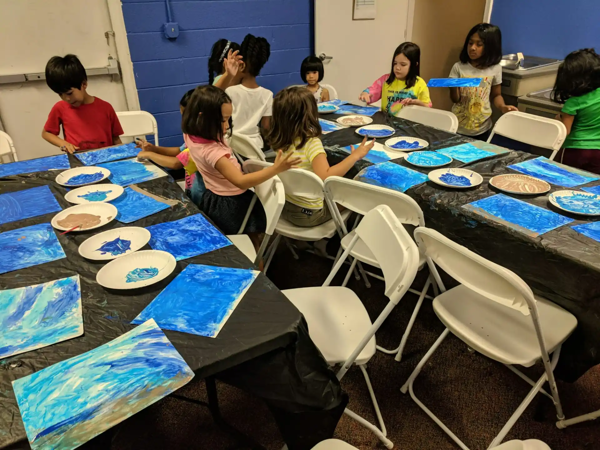 a group of children sitting around a table with plates on it