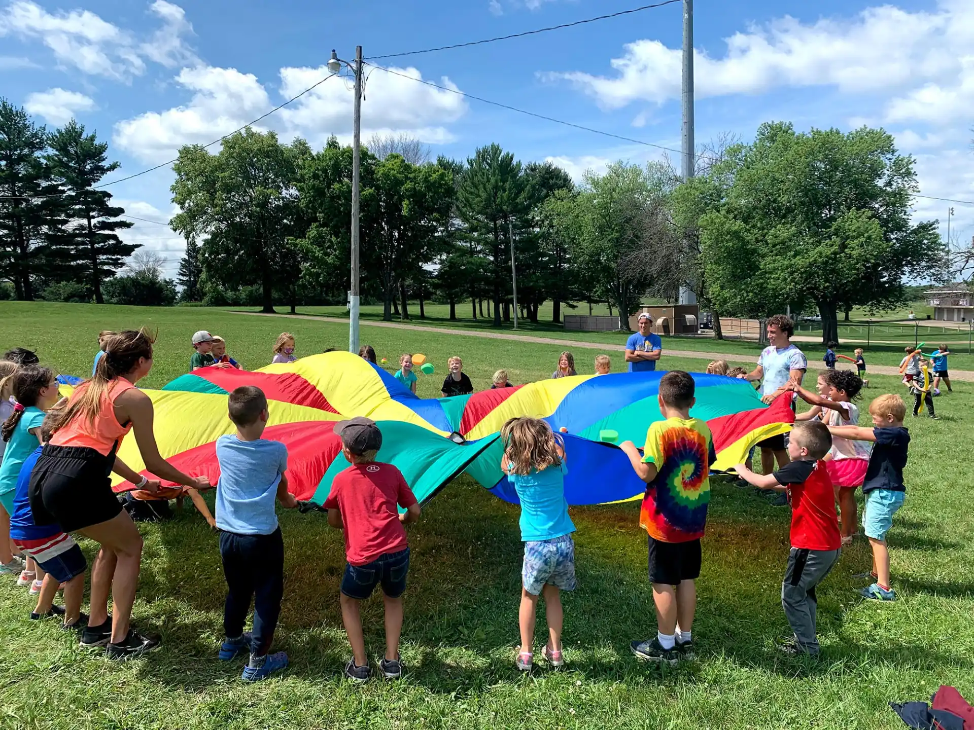 a group of people playing with a large colorful kite