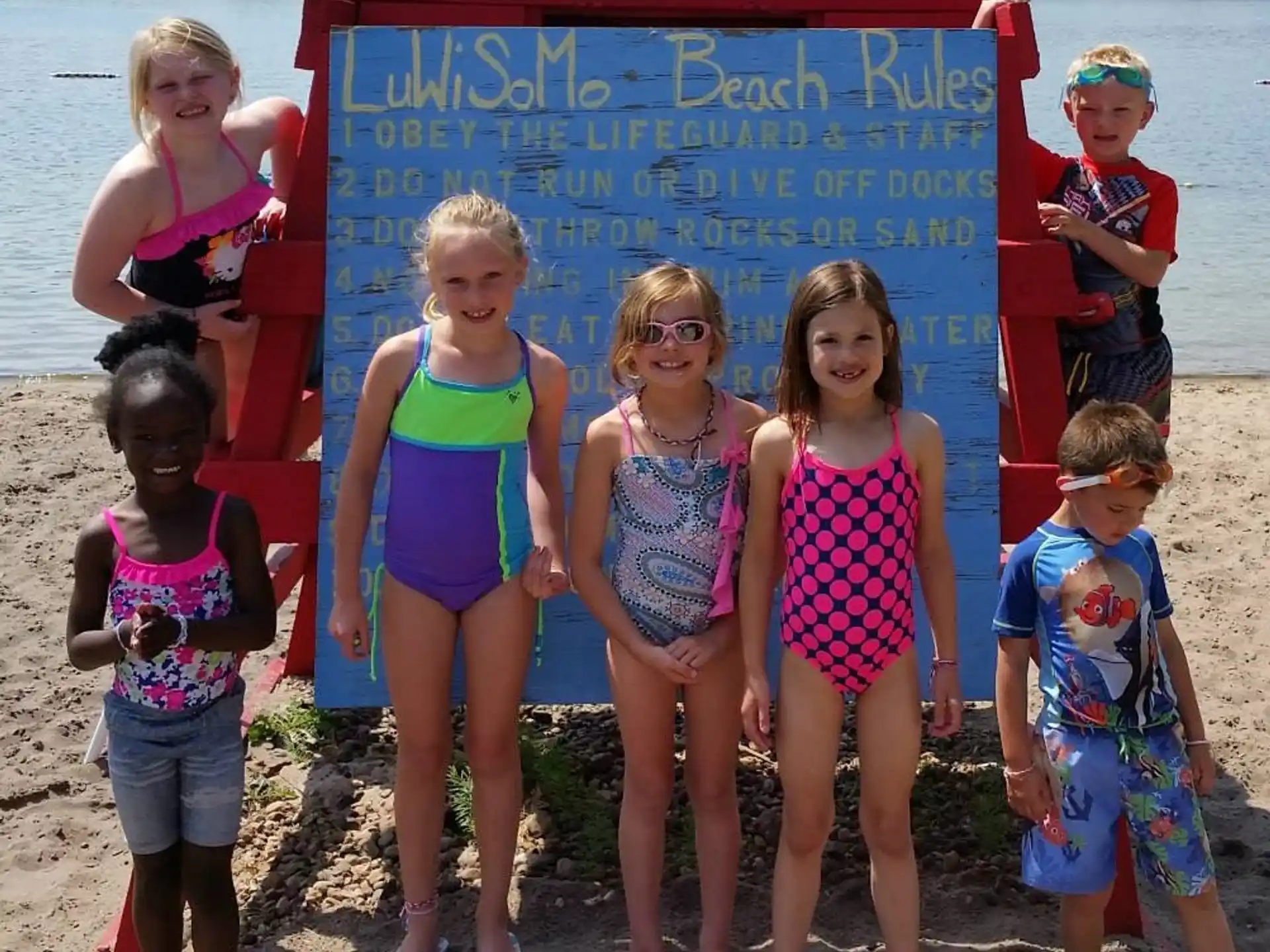 a group of children posing for a photo in front of a sign