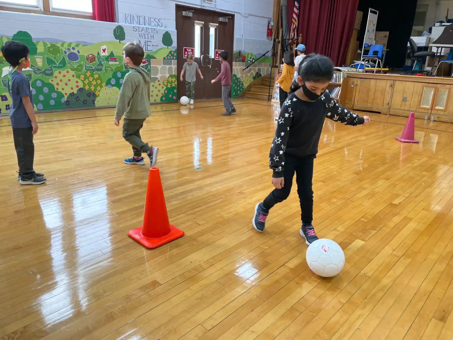 a group of kids playing with a ball on a wooden floor