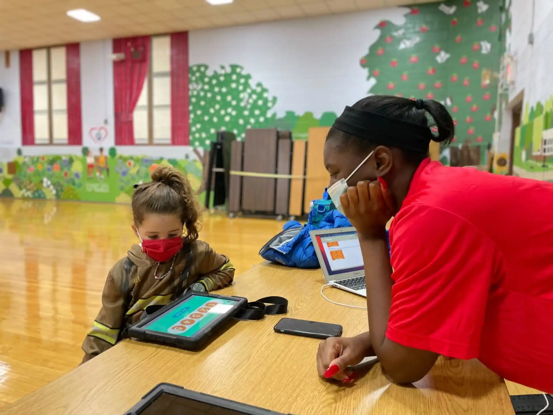 a person and a child sitting at a table with a tablet