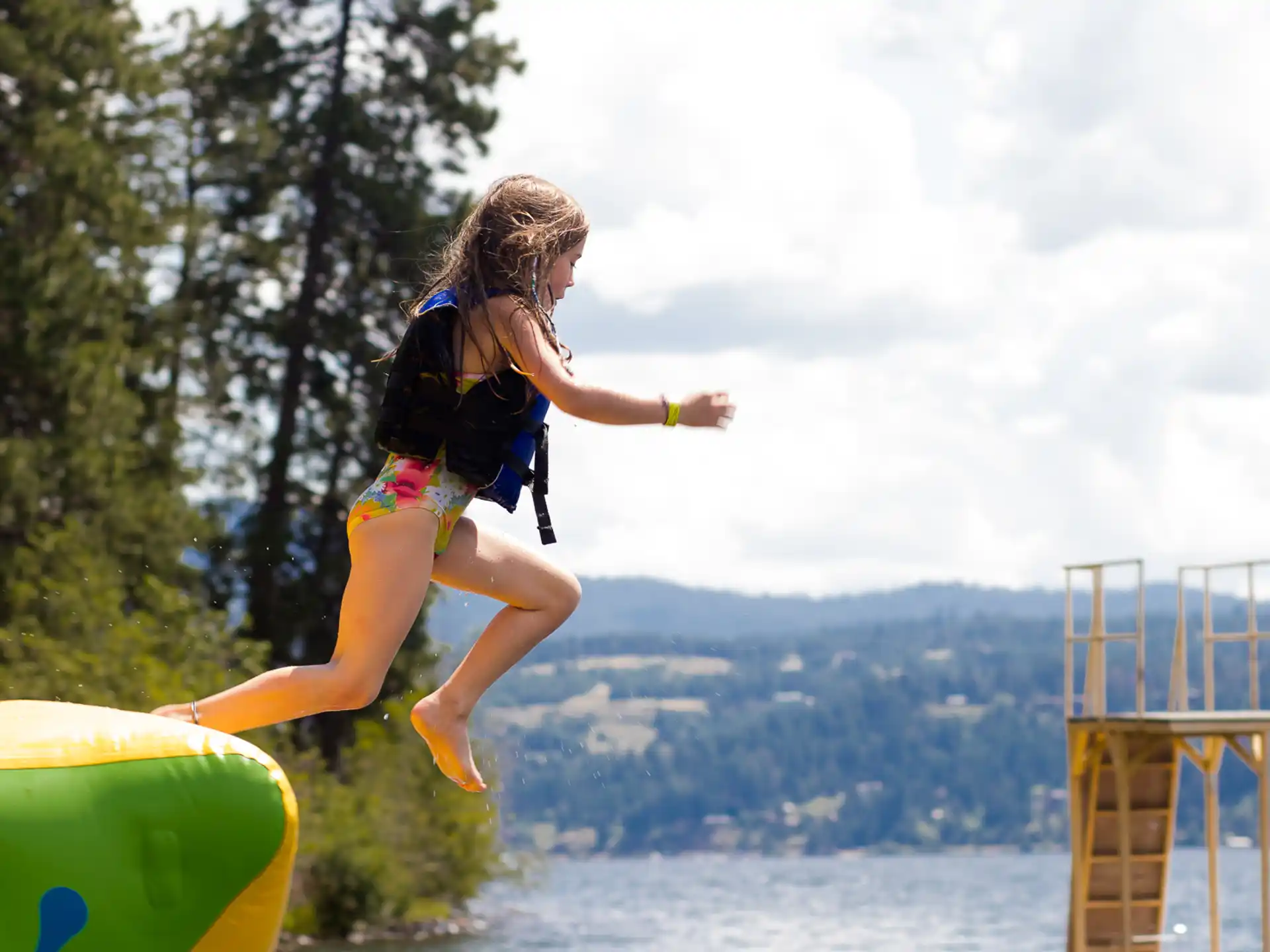 a girl jumping on a yellow and blue playground toy