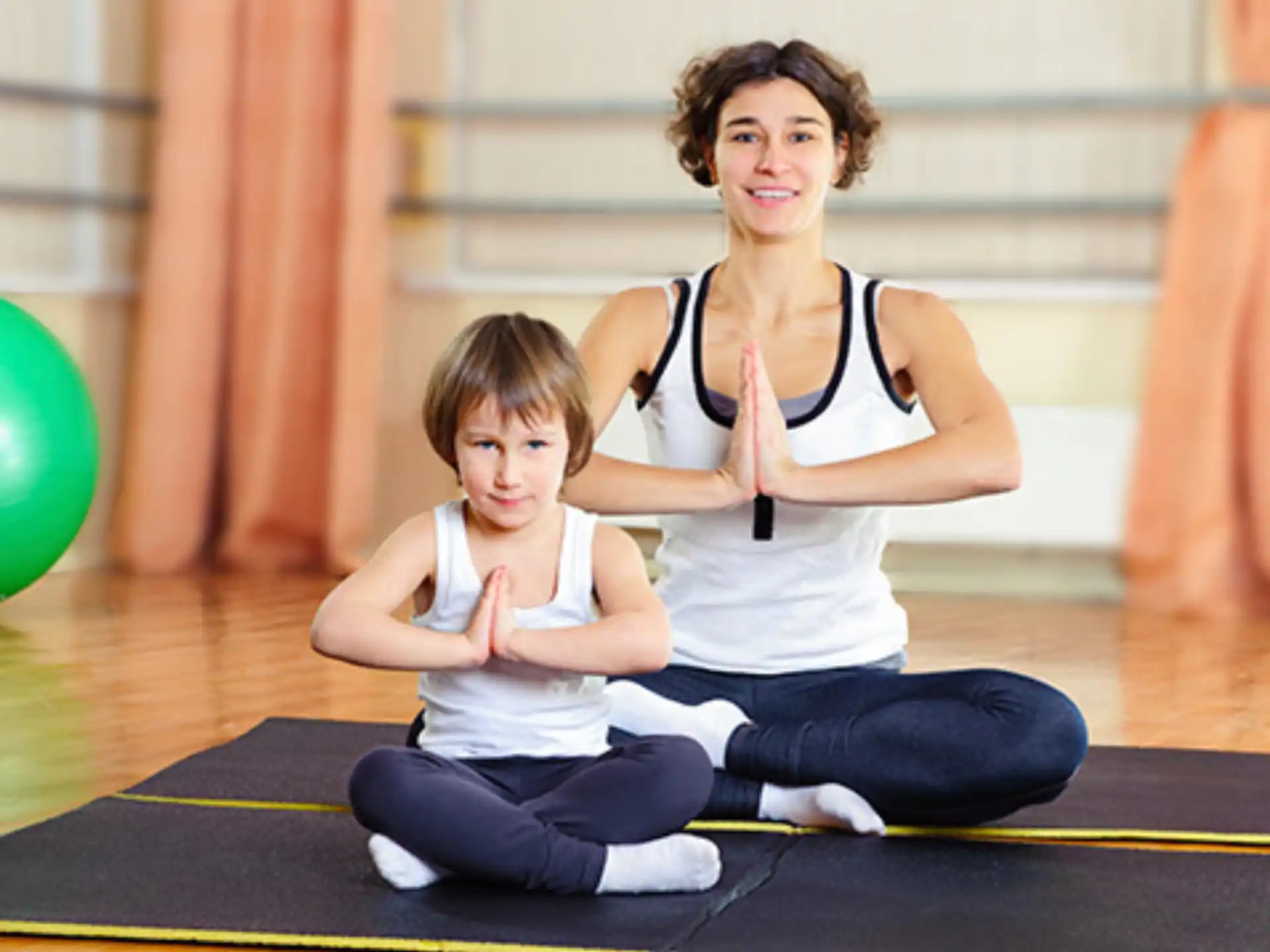 a woman and a child sitting on the floor with a ball