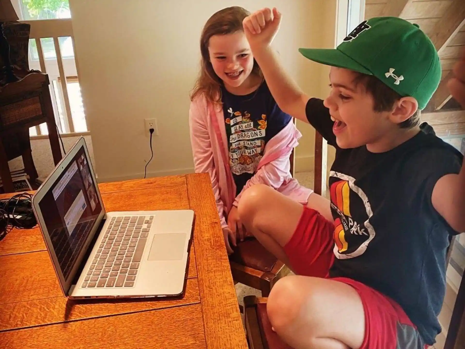 a couple of kids sit near a laptop