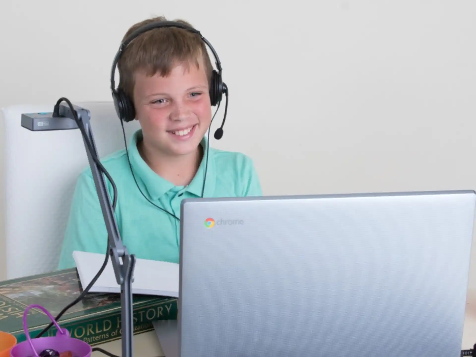 a person wearing headphones and sitting at a desk with a laptop