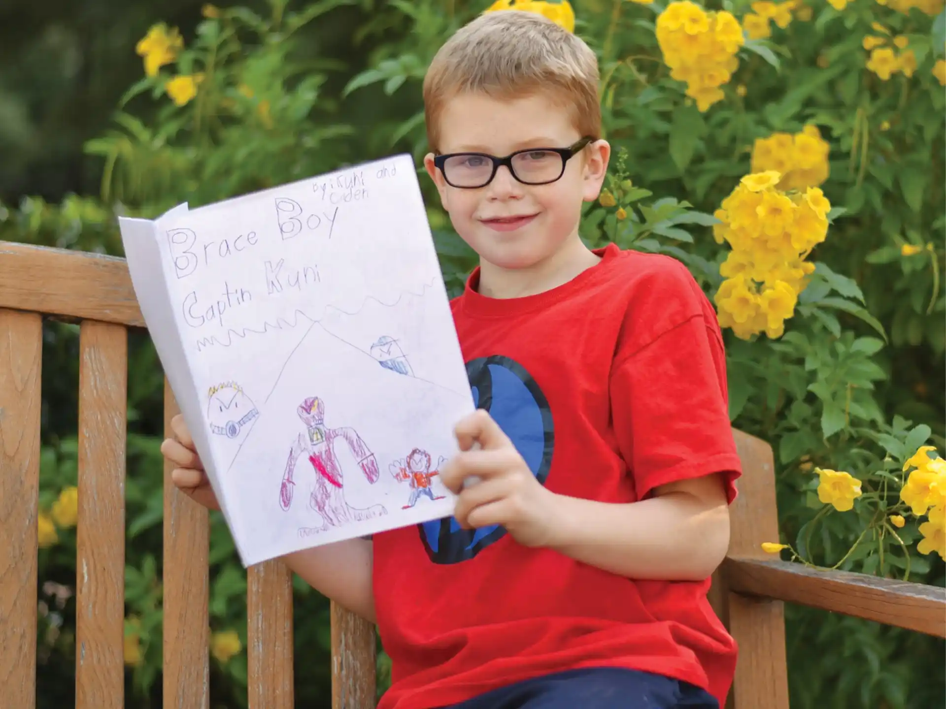 a boy sitting on a bench and holding a paper