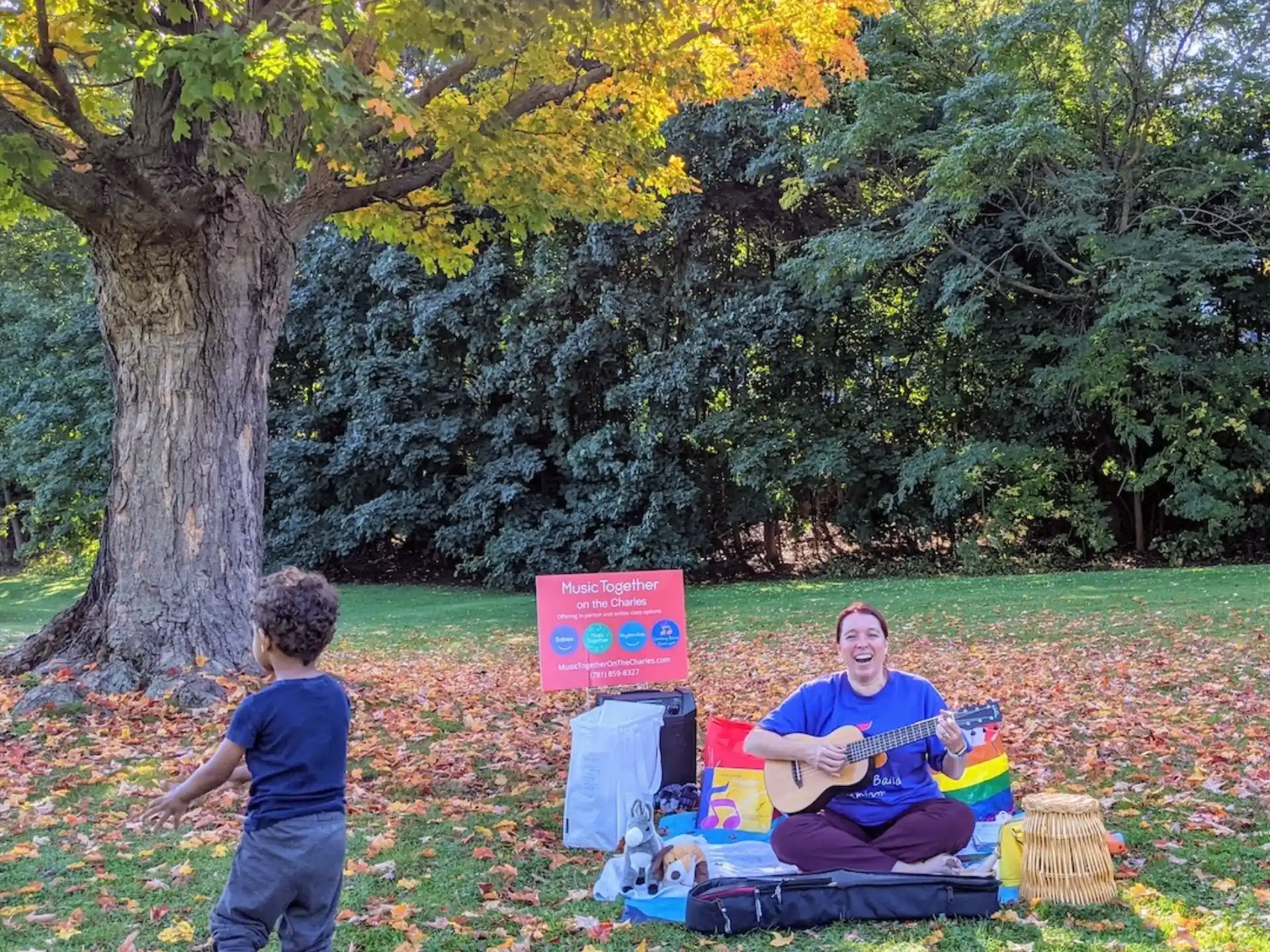 a person and a child sitting on a blanket in a park