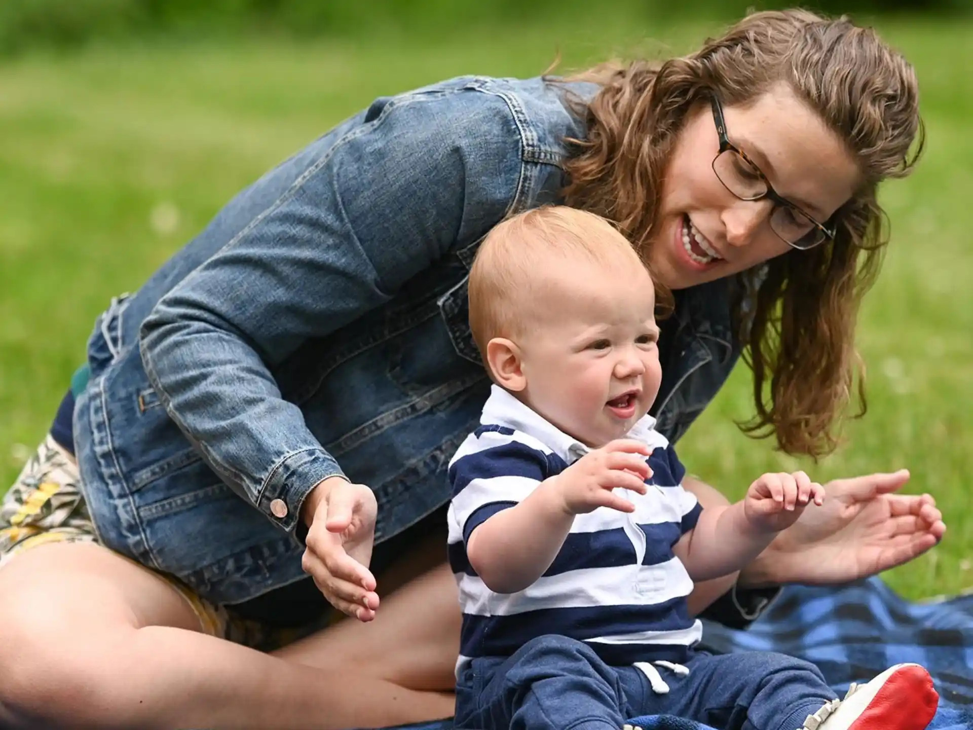 a person lying on grass holding a baby