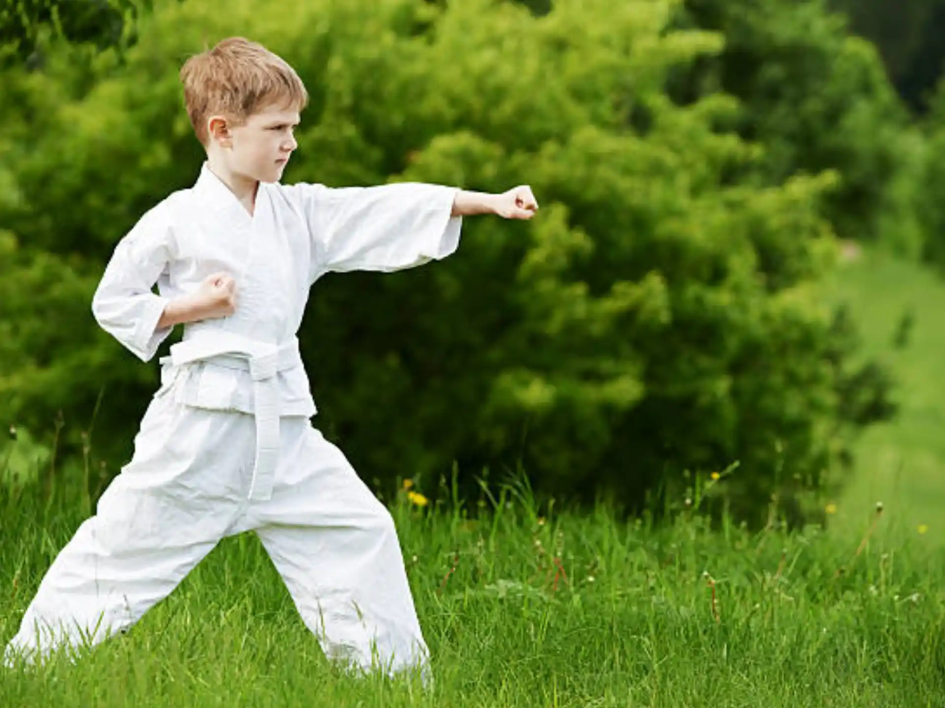 a boy in white clothes running in a grassy area