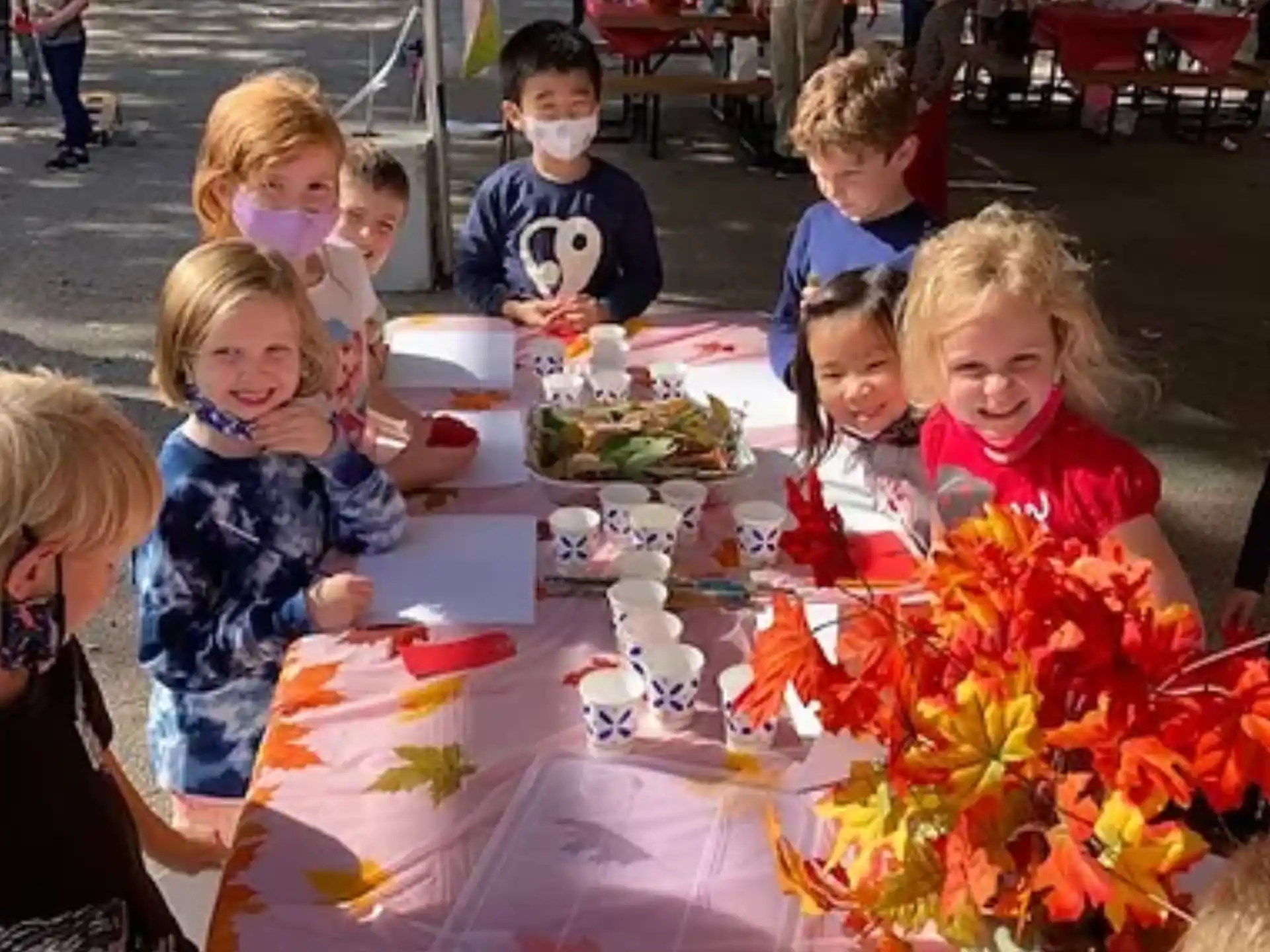 a group of children sitting at a table with food and drinks