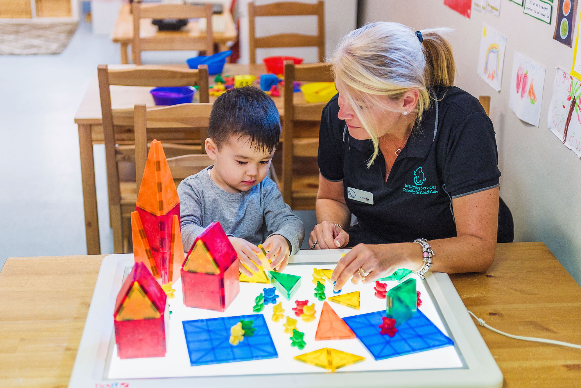 a person and a child playing with toys on a table
