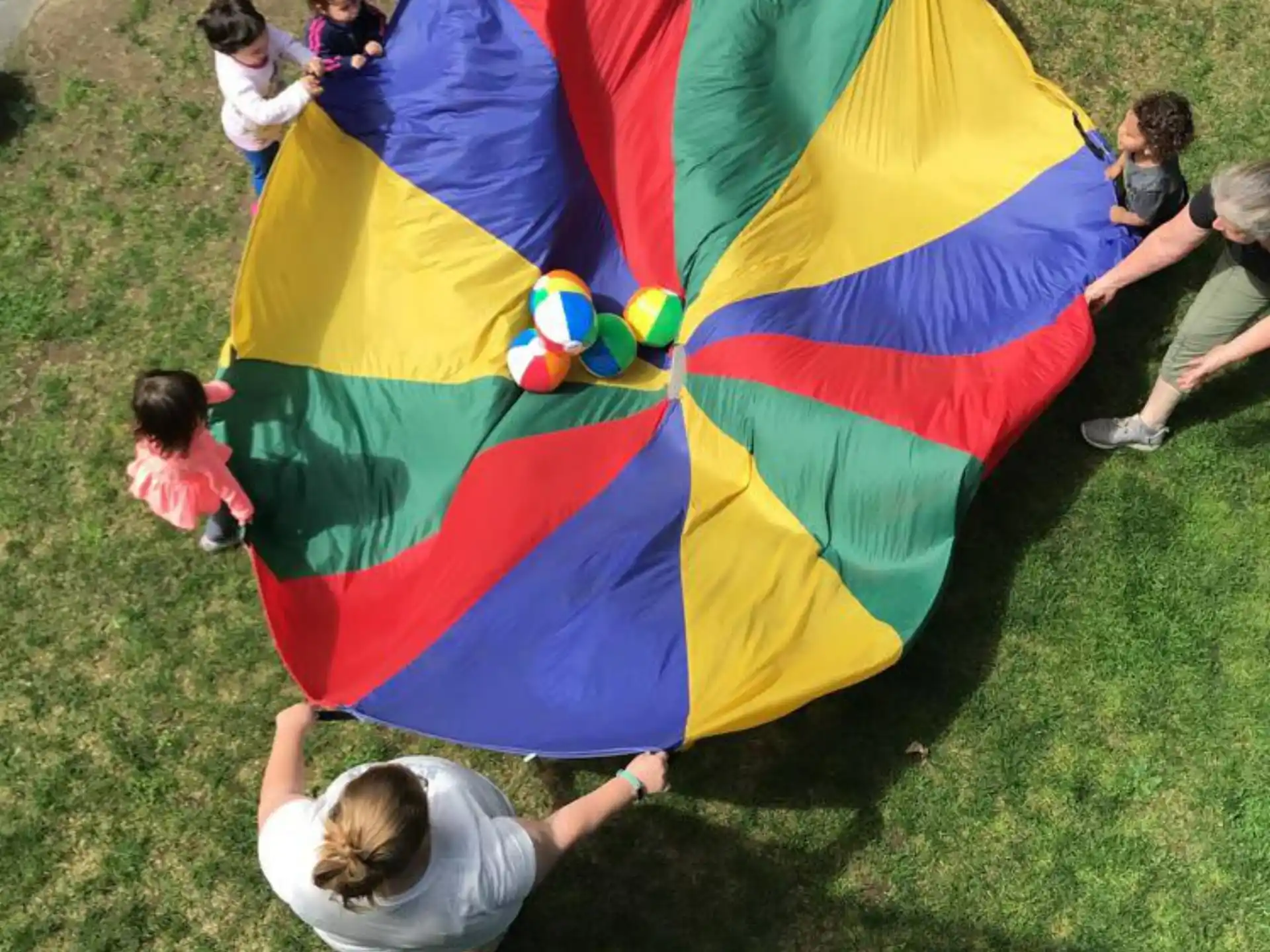 a group of people sitting on the grass with a colorful kite