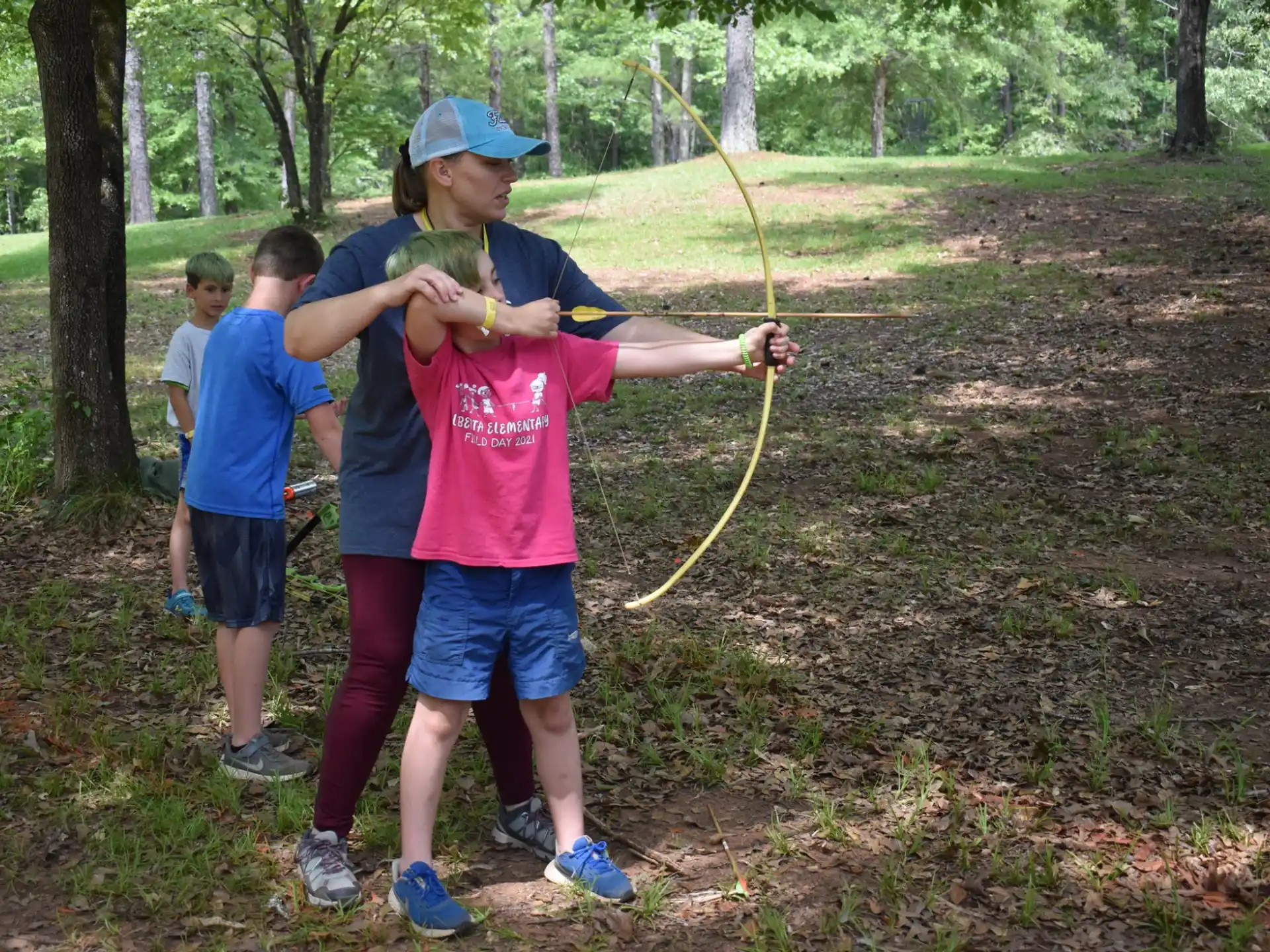 a group of kids holding bows and arrows in a forest