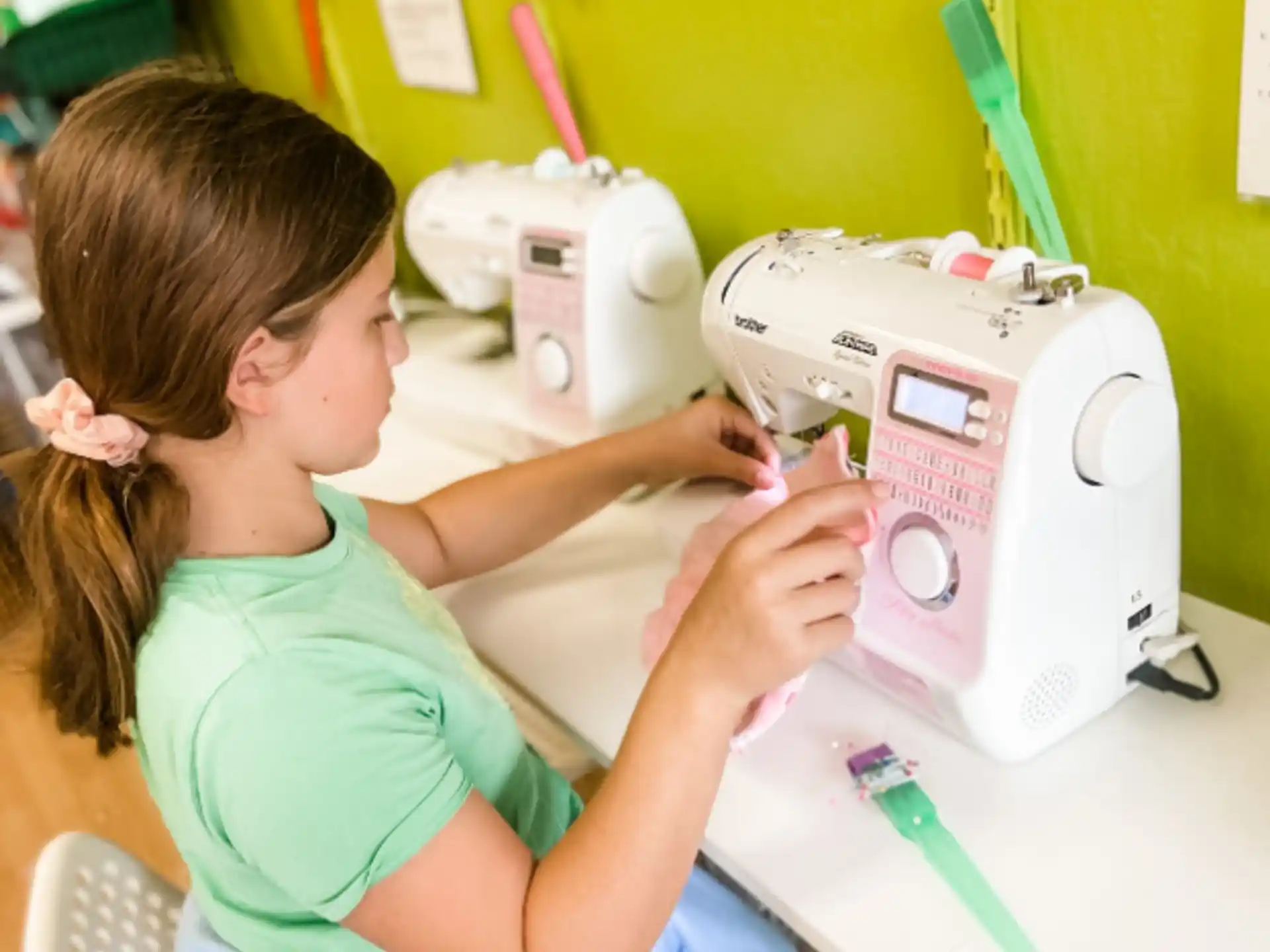 a young girl using a sewing machine