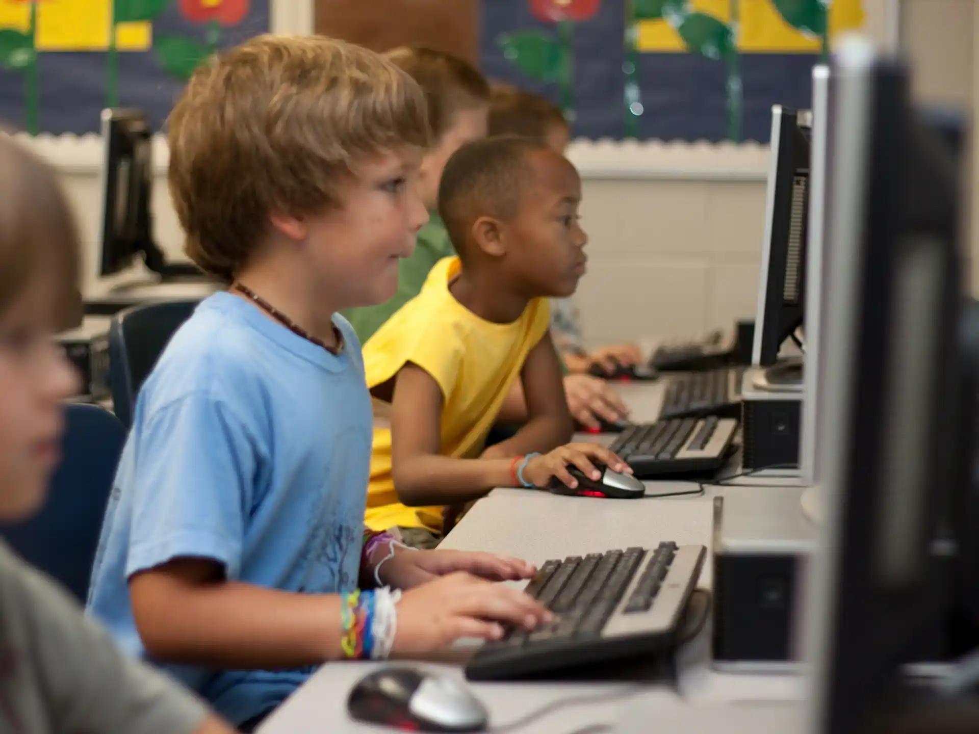 a group of boys sitting at a computer
