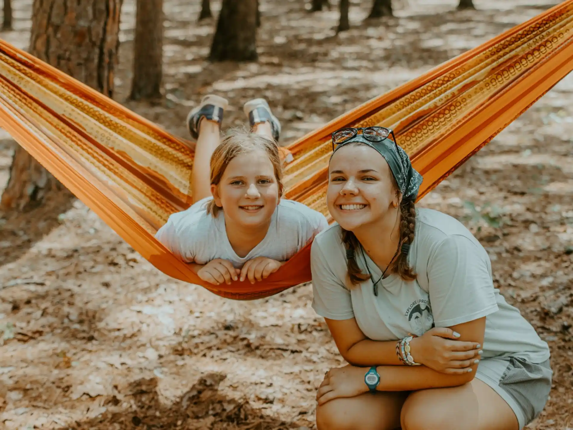 a couple of women sitting in a hammock in the sand