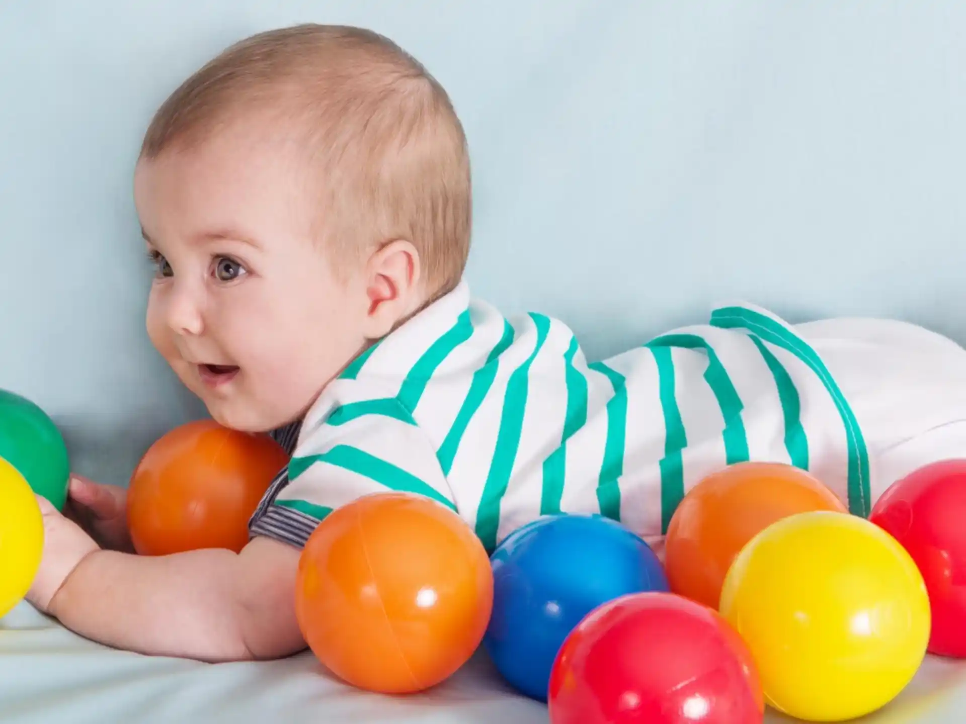 a baby lying in a pile of colorful balls