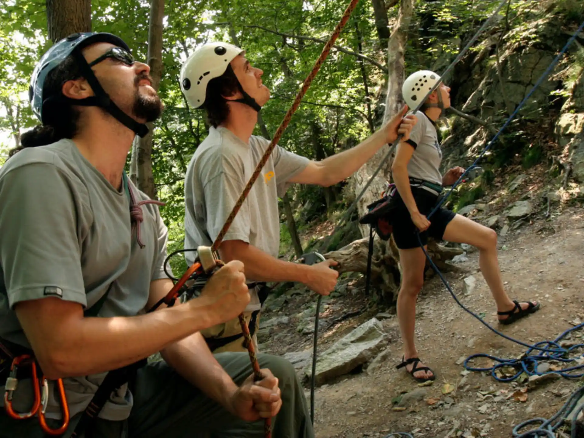 a group of people wearing helmets and harnesses on a rock