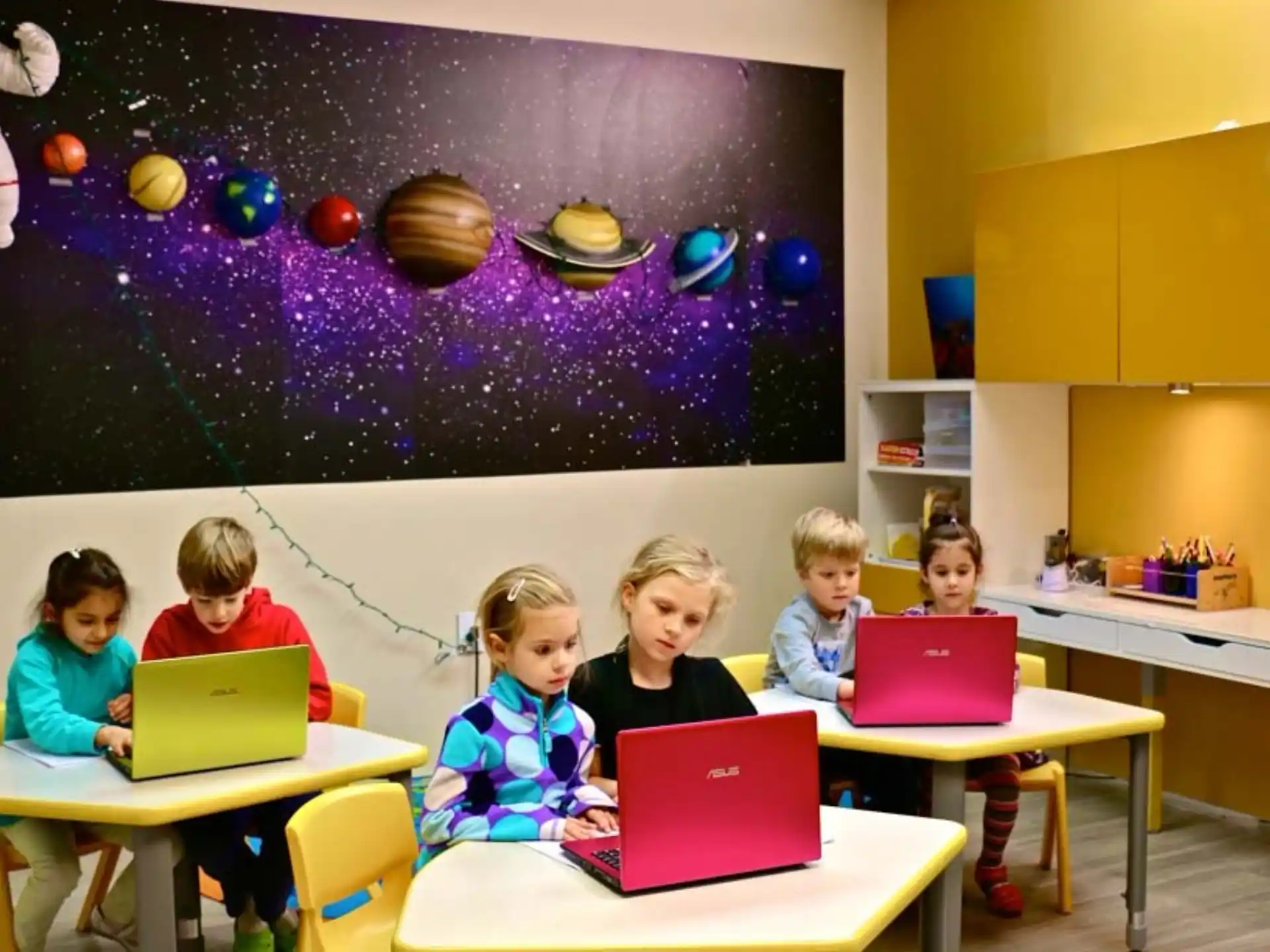 a group of children sitting at desks with laptops