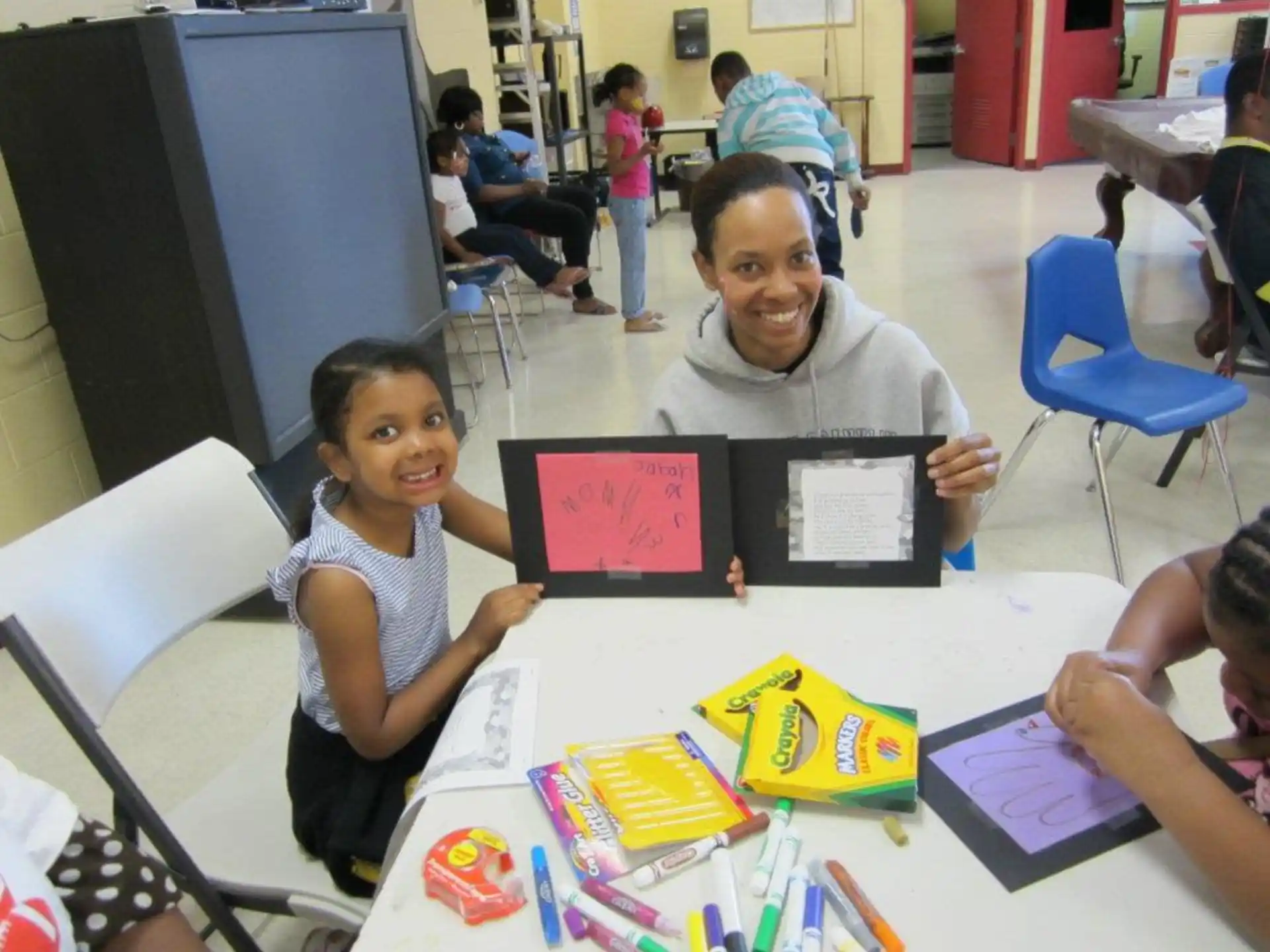 a person and a girl sitting at a table with a tablet