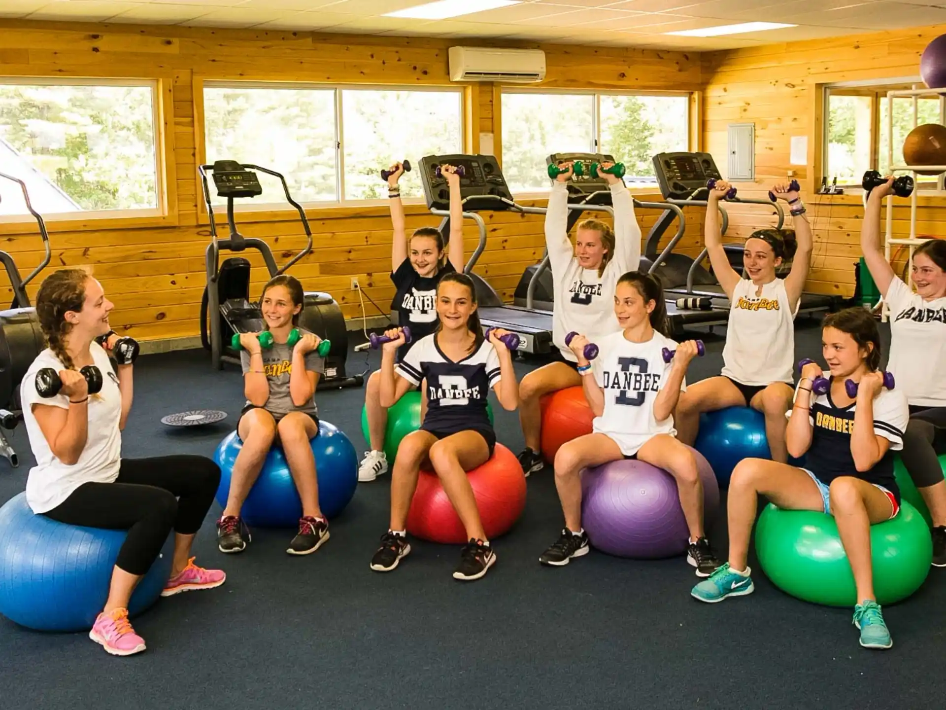 a group of people sitting on exercise balls in a gym