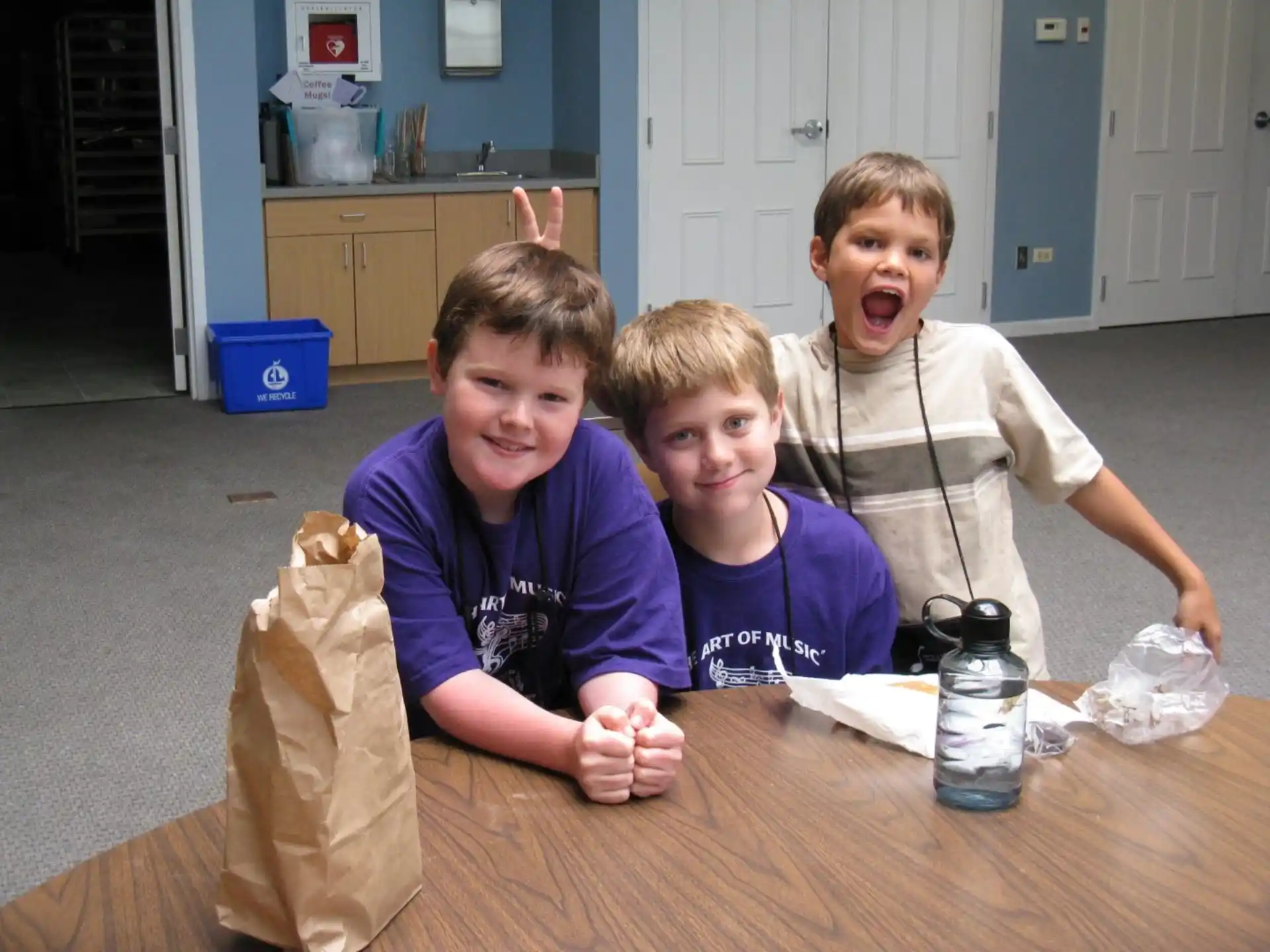 a group of boys sitting at a table with a bag of chips