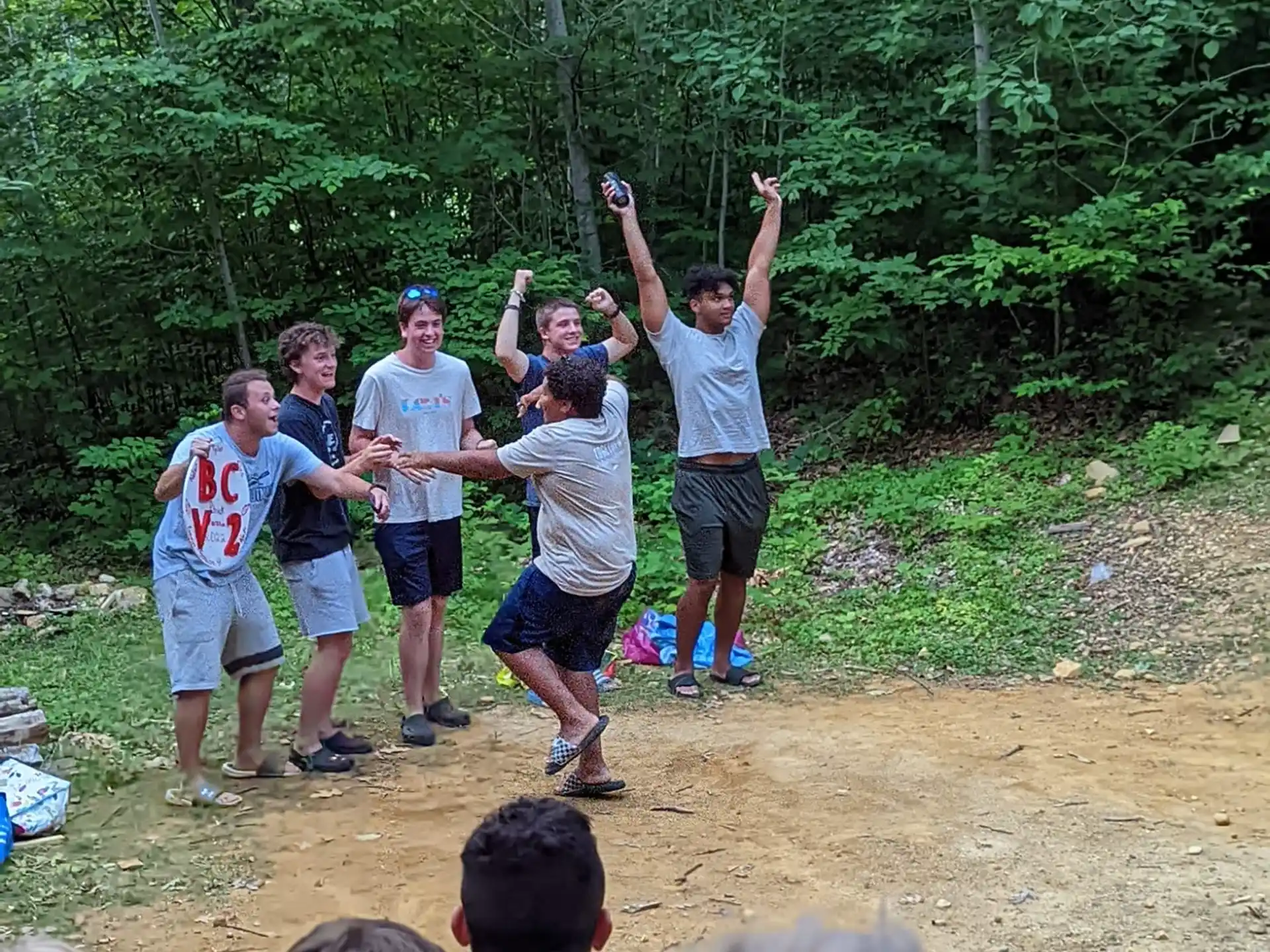 a group of people standing on dirt with their arms raised