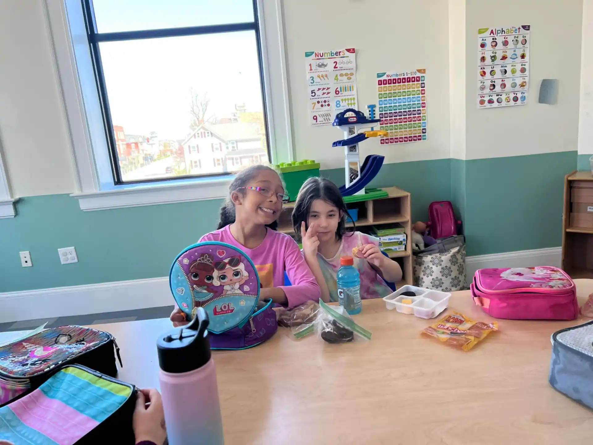 a woman and a girl sitting at a table with a basket and a window