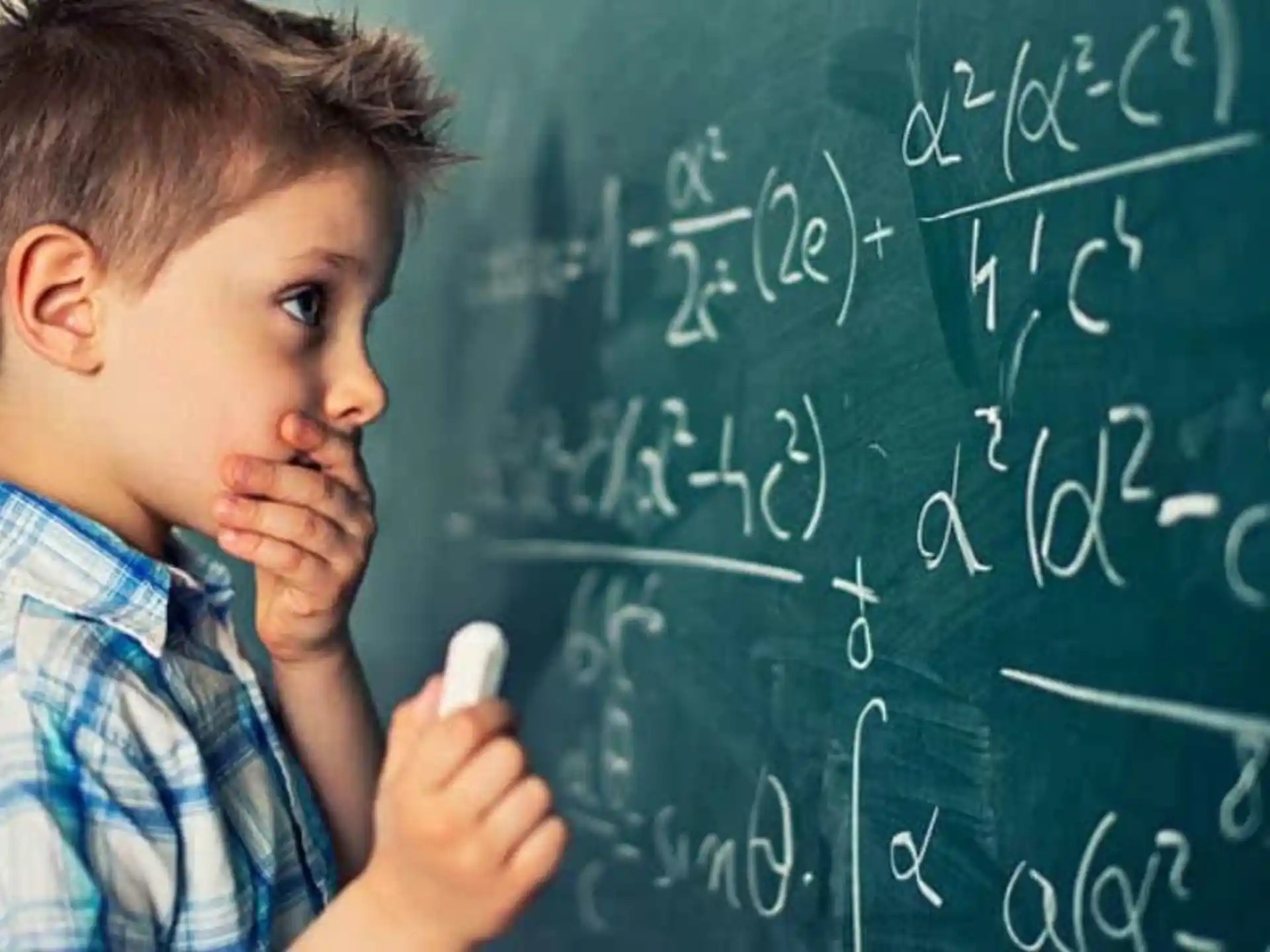 a young boy writing on a chalkboard