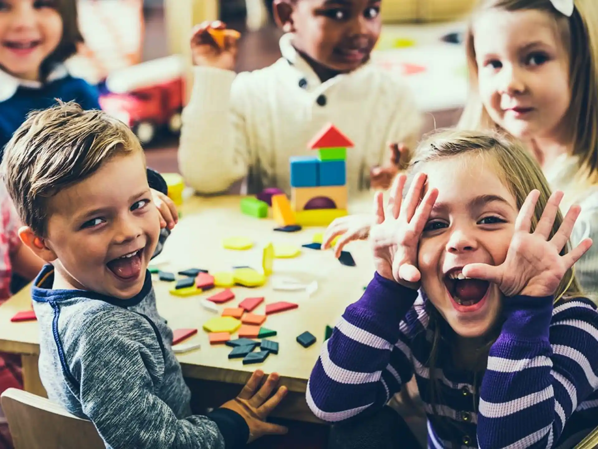 a group of children sitting at a table with their hands up