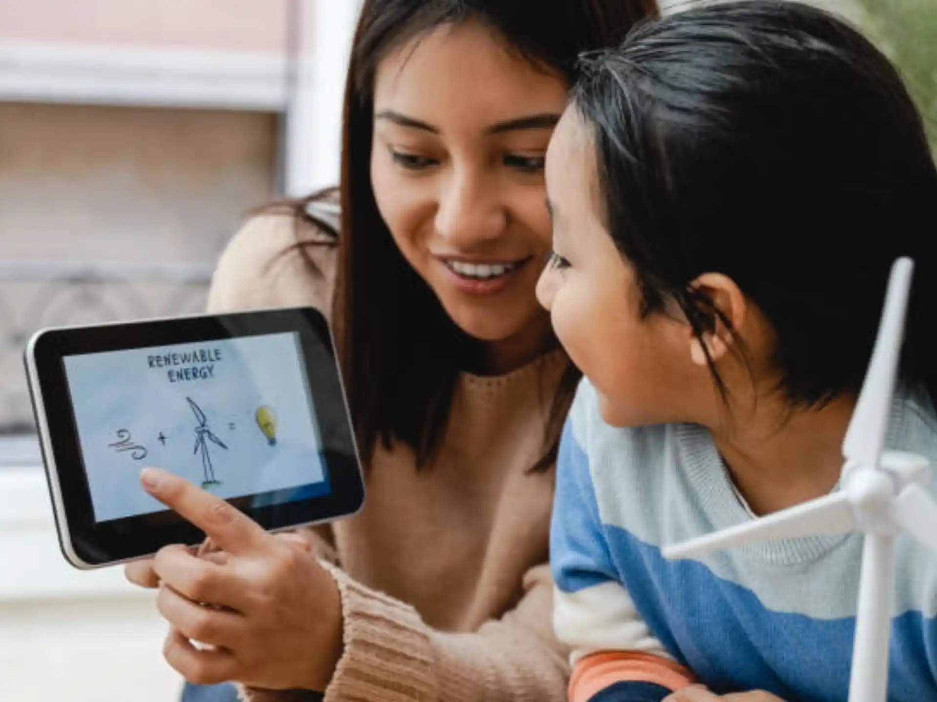 a woman showing a girl something on the tablet