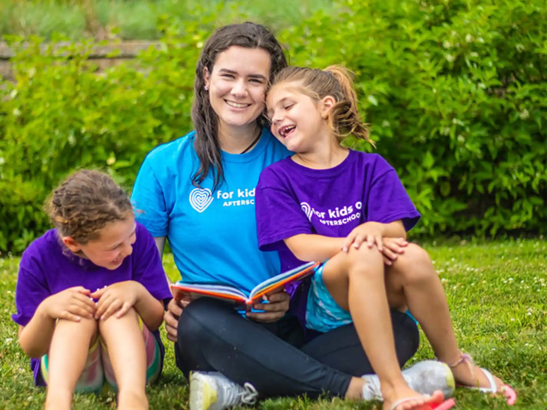 a person and two children sitting on grass