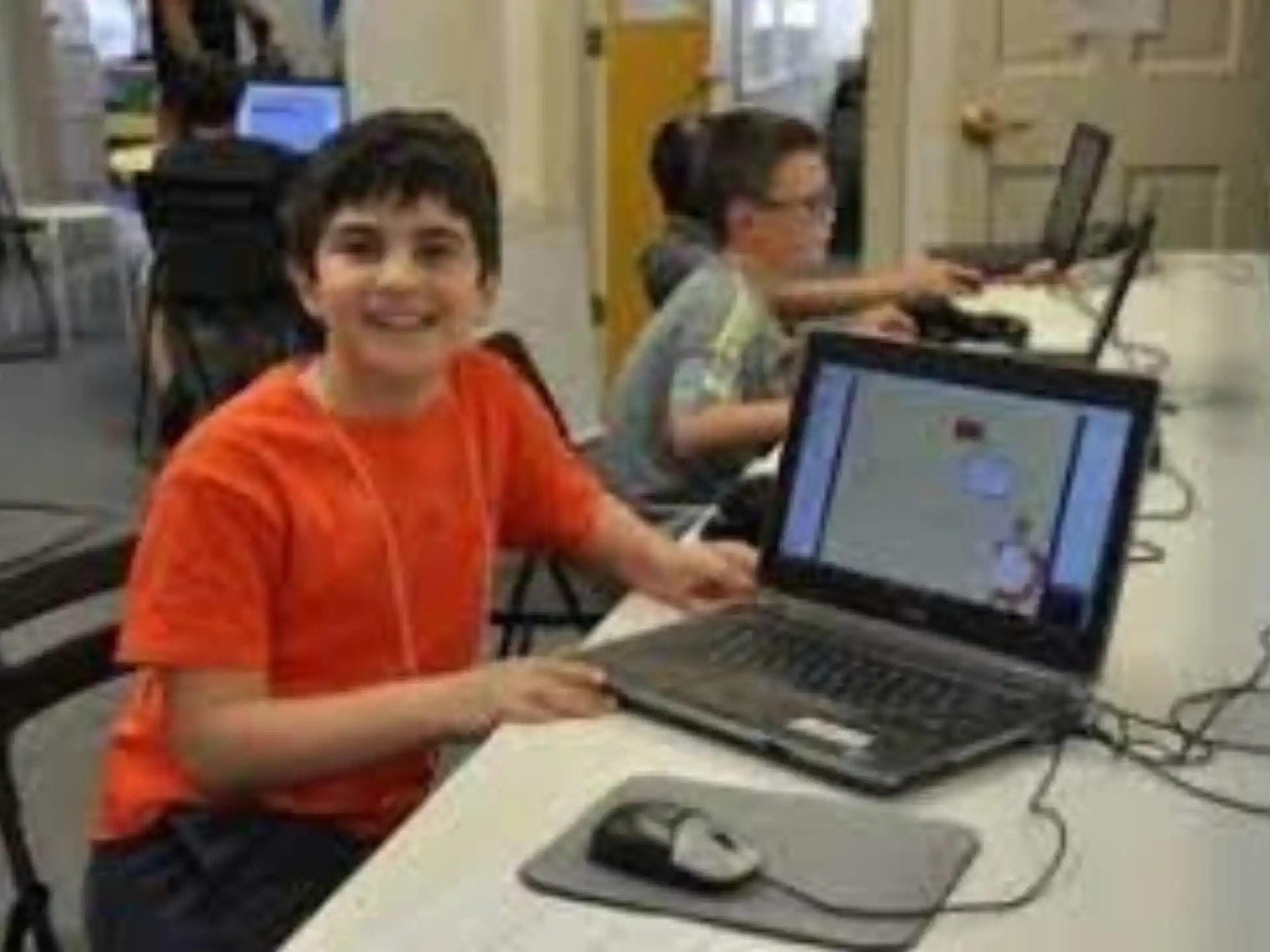 a boy sitting at a desk with a laptop