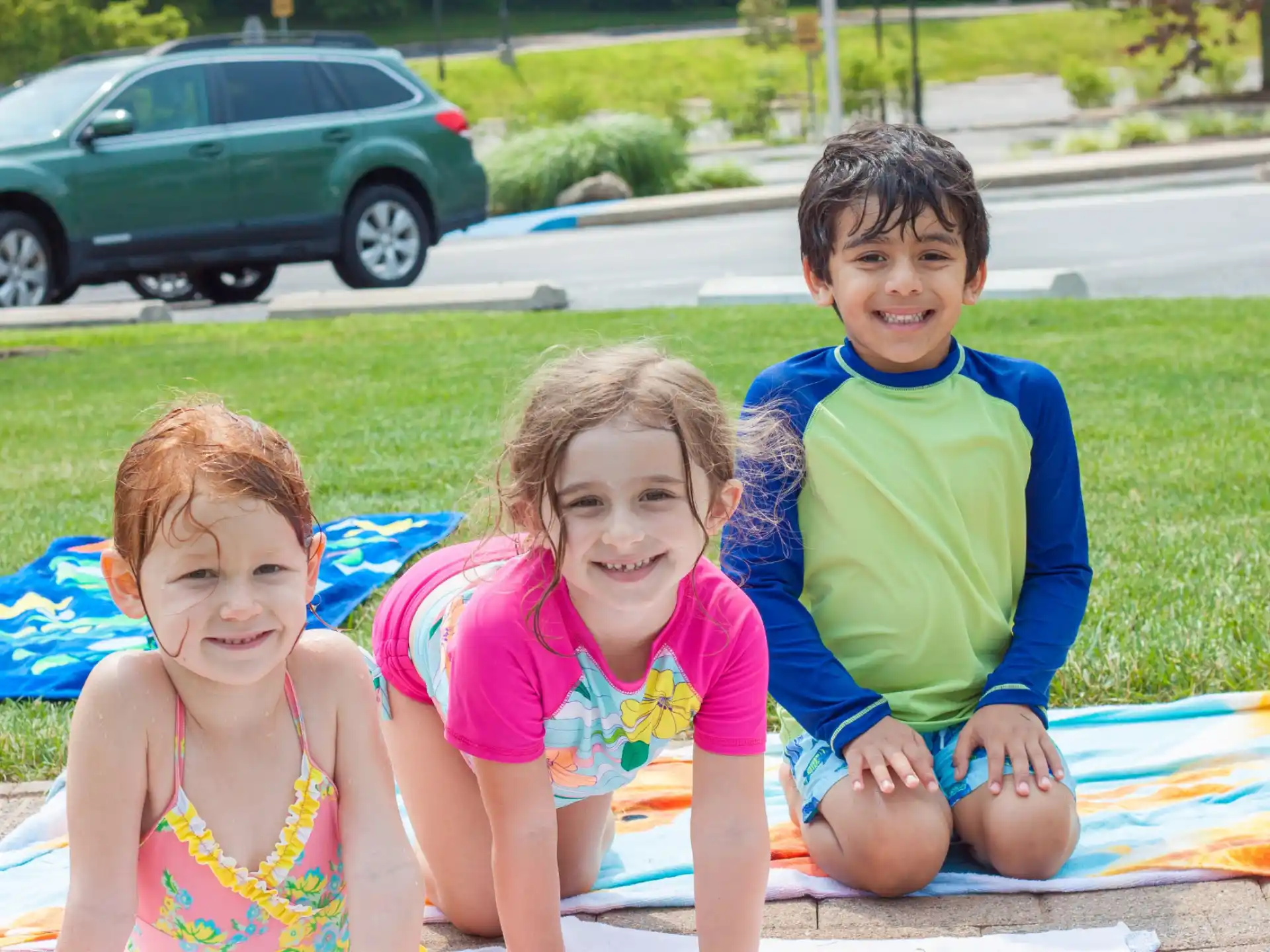 a group of children sitting on a blanket in a grassy area