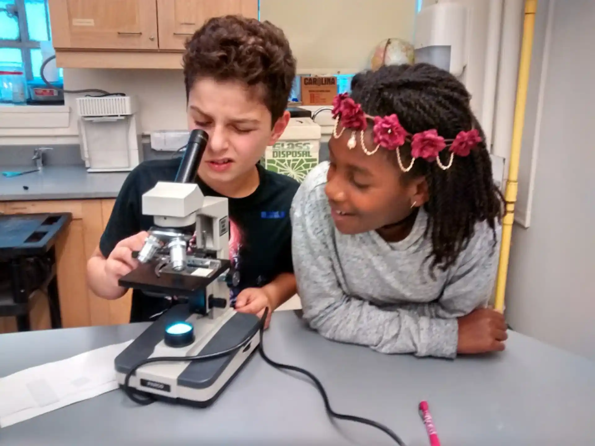a young girl and a young girl looking at a microscope