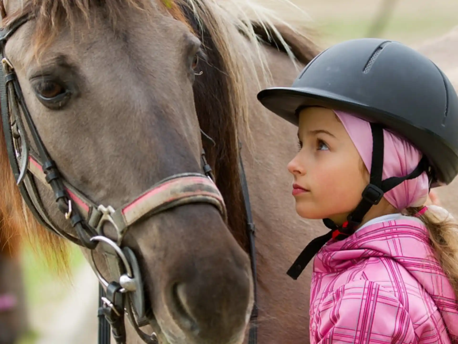 a girl wearing a helmet and riding a horse
