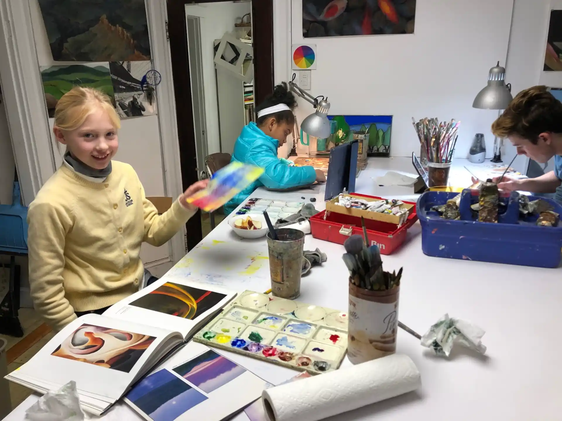 a group of children sitting at a table with books and toys